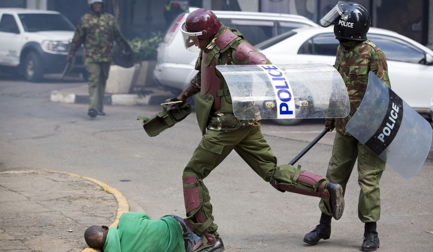 FILE - In this Monday, May 16, 2016 file photo, a Kenyan riot policeman repeatedly kicks a protester as he lies in the street after falling down while trying to flee from them, during a protest in downtown Nairobi, Kenya. In an incident that has stirred anger and condemnation across Kenya, a policeman is seen beating and kicking one protester who had fallen on a road curb, while the U.S. and human rights activists have condemned violence by Kenyan police at the opposition protest for election reforms. (AP Photo/Ben Curtis, File)