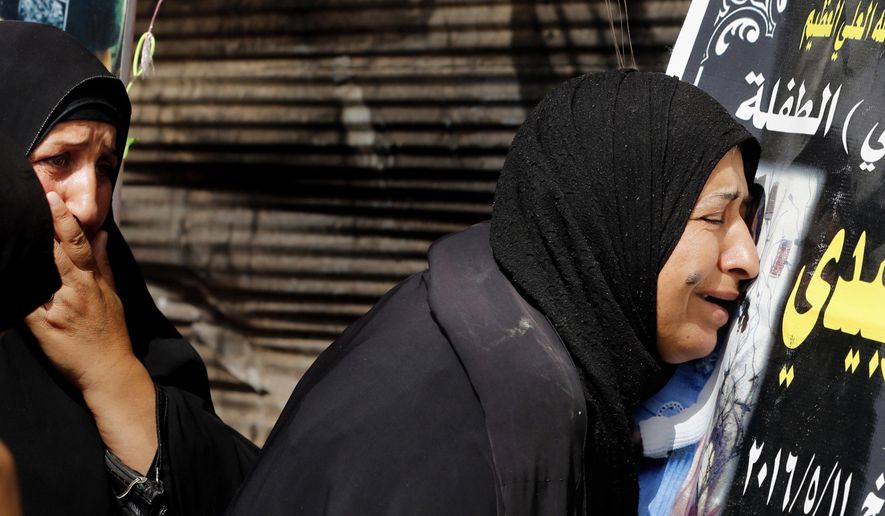 In this Saturday, May 14, 2016 photo, family members of truck bomb victims grieve at the bombing site in Baghdad's Sadr City, Iraq. This sprawling district in northeast Baghdad has witnessed some of the worst violence to hit Baghdad this year as Islamic State group fighters have increasingly tuned to insurgent style terrorist attacks in the face of mounting battlefield losses in Iraq. Along Sadr City's main thoroughfares, fresh black posters bare the names and pictures of the more than 80 killed in the past week. The single deadliest attack this year was also in Sadr City in late February when a double car bombing killed more than 70 and wounded more than 100. (AP Photo/Karim Kadim)