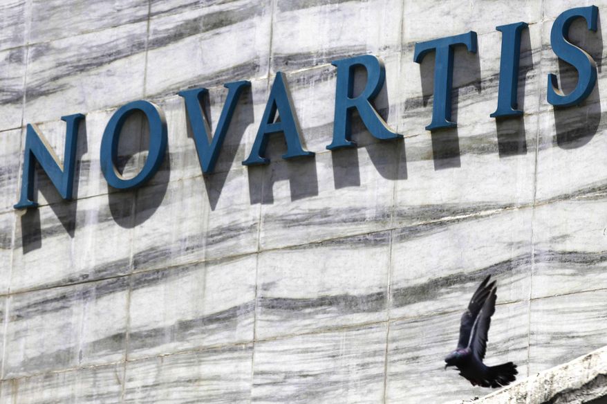 FILE - In this April 1, 2013 file photo, a dove flies near the logo of Novartis India Limited at their head office in Mumbai, India. Colombia’s government announced on Tuesday, May 17, 2106, that it is giving pharmaceutical giant Novartis a few weeks to lower prices on a popular cancer drug or see its monopoly on production of the medicine broken and competition thrown open to generic rivals. (AP Photo/Rafiq Maqbool, File)