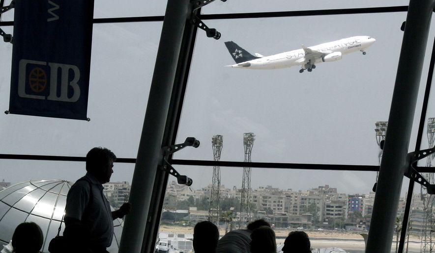 Western tourists stand watching an EgyptAir plane as it takes off at Cairo International Airport on June 4, 2008. (Associated Press) ** FILE **