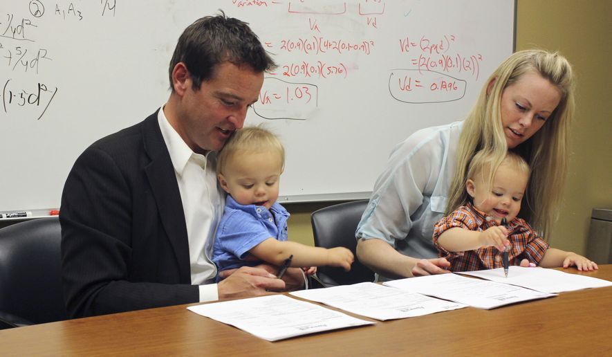Craig McCarthy and Rebecca Amble read over consent forms to allow their 16-month-old identical twins, Kamper, left, and Sayers to be part of the Avera Twin Register on Wednesday, May 18, 2016, in Sioux Falls, S.D. Sioux Falls-based Avera Health on Wednesday launched the register hoping twins who live in the Midwest will contribute DNA to the project aimed at gaining insights into traits and diseases specific to the region. (AP Photo/Regina Garcia Cano)