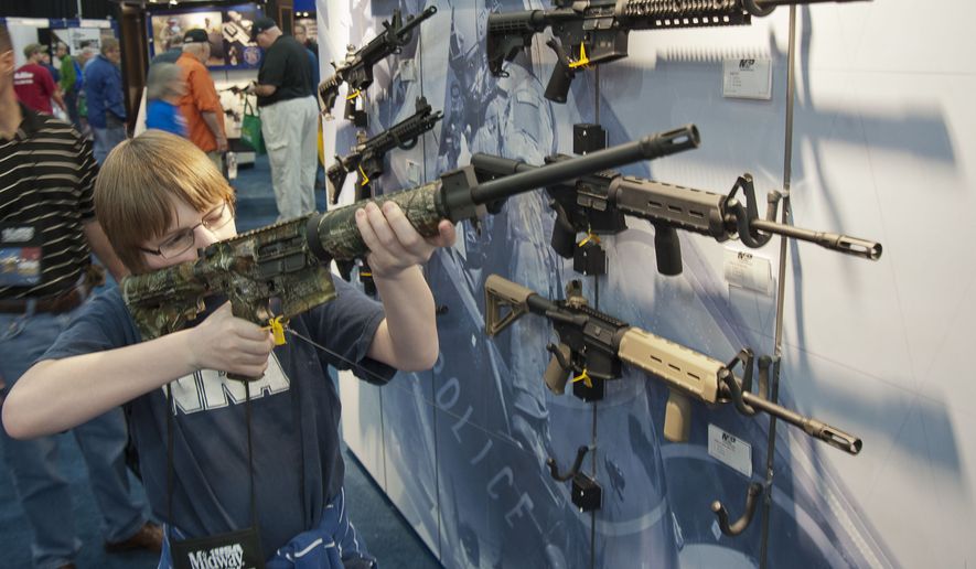 A young man who chose not to give his name sizes up an assault-style rifle during the National Rifle Association&#x27;s annual convention on May 3, 2013, in Houston. (Associated Press)