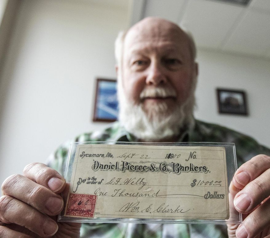 In this April 21, 2016, photo, Sycamore, Ill. Mayor Ken Mundy shows a check in his city hall office from Daniel Pierce & Co. Bankers for $1,000 dollars that was processed in 1900. Daniel Pierce & Co. Bankers once owned the building that city hall is currently located. (Danielle Guerra/Daily Chronicle via AP) MANDATORY CREDIT; CHICAGO TRIBUNE OUT