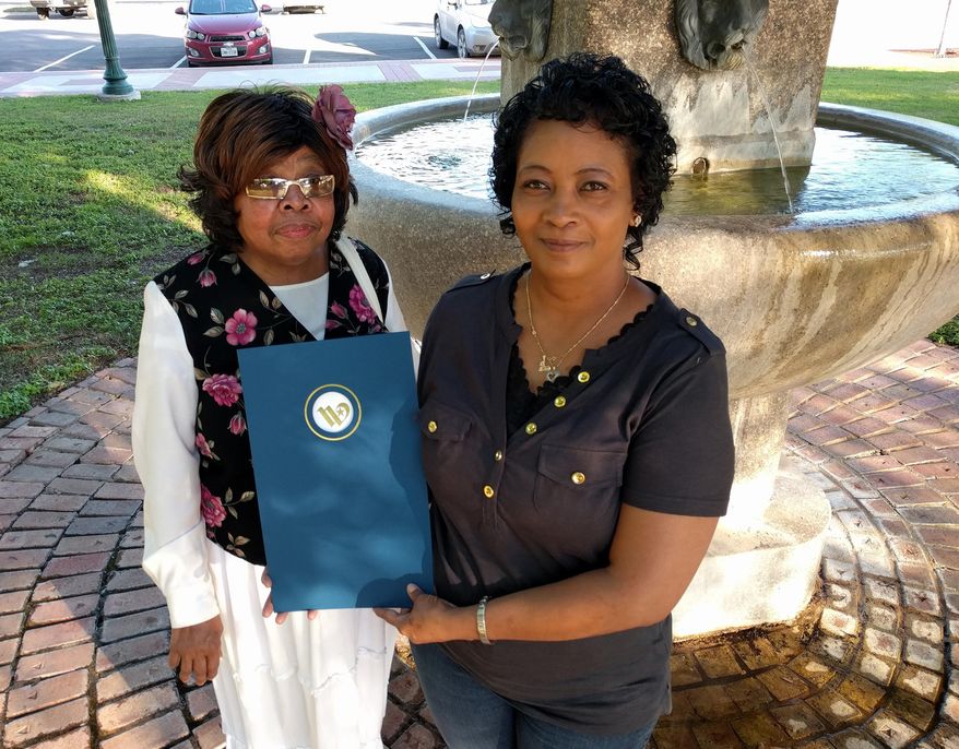In this May 2, 2016 photo, sisters Mary Pearson, left, and Evelyn Denise Mitchell hold the mayoral proclamation recognizing the anniversary of the Jesse Washington lynching in Waco, Texas. The sisters grew up hearing stories of the lynching from their grandmother, who was a relative of Washington. (JB Smith/Waco Tribune Herald, via AP)