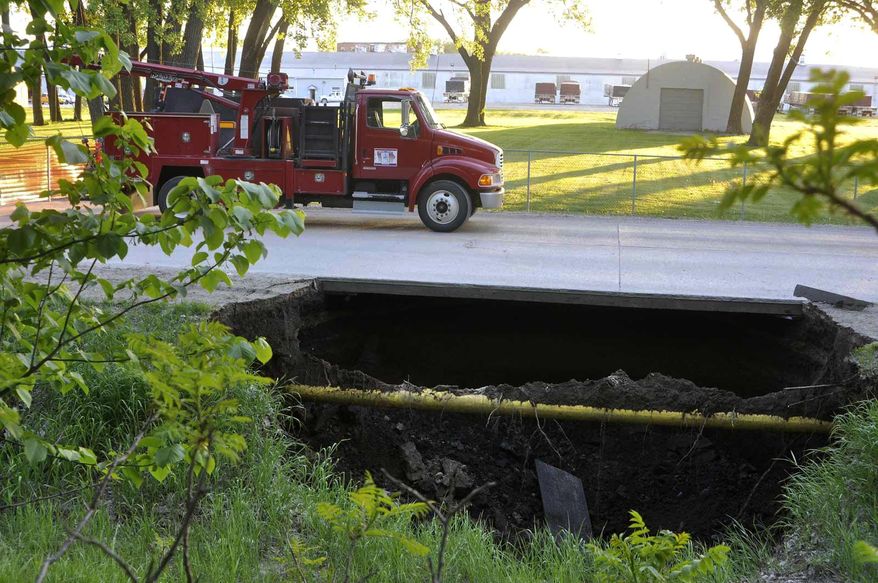 In this Wednesday, May 18, 2016 photo, a sinkhole forces the closure of a street in Fort Dodge, Iowa. (Chad Thompson /The Messenger via AP) MANDATORY CREDIT