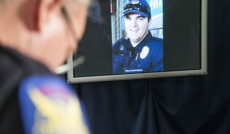The image of Phoenix police officer David Glasser is displayed during a news conference as Phoenix Police PIO Vince Lewis, left, holds his head down on Thursday May 19, 2016 in Phoenix. Glasser died Thursday, a day after being wounded during a shooting that left a burglary suspect dead. (Nick Oza/The Arizona Republic via AP) MARICOPA COUNTY OUT; MAGS OUT; NO SALES; MANDATORY CREDIT