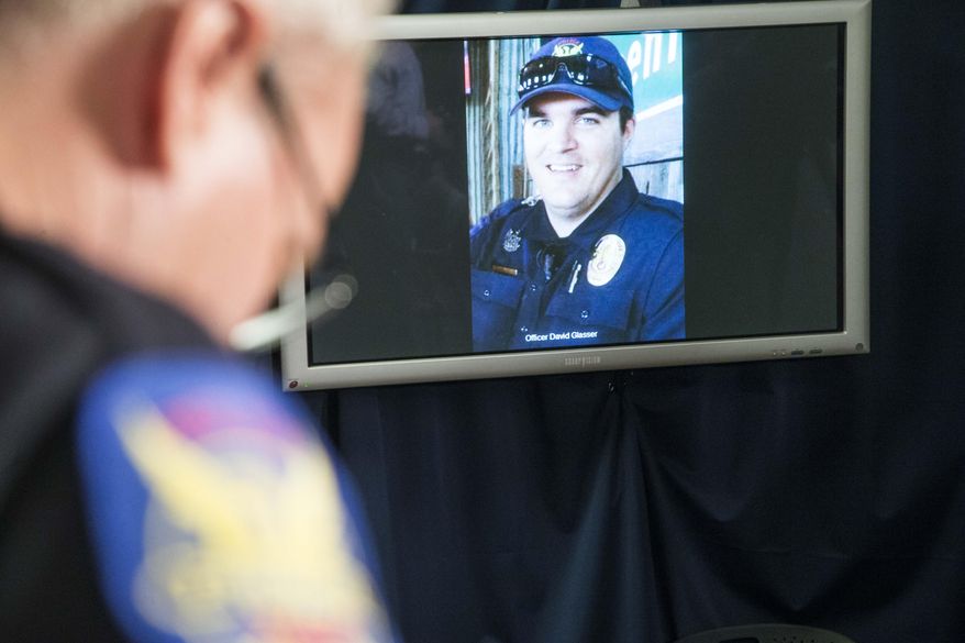 The image of Phoenix police officer David Glasser is displayed during a news conference as Phoenix Police PIO Vince Lewis, left, holds his head down on Thursday May 19, 2016 in Phoenix. Glasser died Thursday, a day after being wounded during a shooting that left a burglary suspect dead. (Nick Oza/The Arizona Republic via AP) MARICOPA COUNTY OUT; MAGS OUT; NO SALES; MANDATORY CREDIT