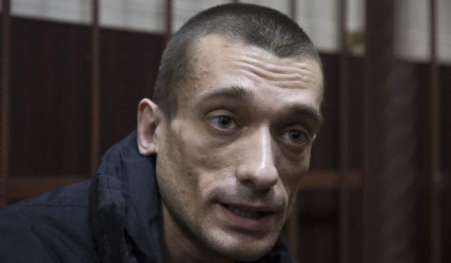FILE - In this Thursday, March 31, 2016 file photo Russian artist Petr Pavlensky speaks to journalists as he sits in a cage in court room in Moscow, Russia. Pavlensky, the Russian artist known for his radical politically charged performances was convicted Thursday, May 19, 2016 of vandalism for a pro-Ukraine protest and sentenced to 16-months in prison.(AP Photo/Ivan Sekretarev, file )