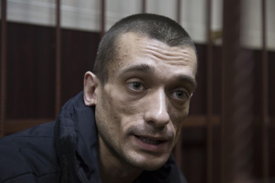 FILE - In this Thursday, March 31, 2016 file photo Russian artist Petr Pavlensky speaks to journalists as he sits in a cage in court room in Moscow, Russia. Pavlensky, the Russian artist known for his radical politically charged performances was convicted Thursday, May 19, 2016 of vandalism for a pro-Ukraine protest and sentenced to 16-months in prison.(AP Photo/Ivan Sekretarev, file )