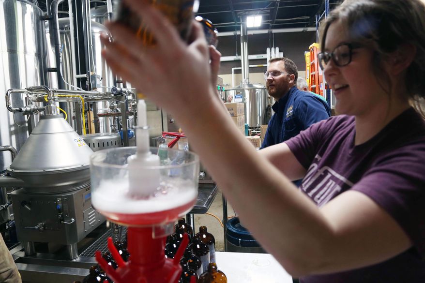 Rebecca Bowen, right, and John Martin, of Confluence Brewing Company bottle root beer developed by students at Roosevelt High school on Wednesday, May 18, 2016, in Des Moines, Iowa. The biology students created the recipe, sourced the ingredients and worked with Confluence to brew and bottle the final product. (Kelsey Kremer/The Des Moines Register via AP) MAGS OUT, TV OUT, NO SALES, MANDATORY CREDIT