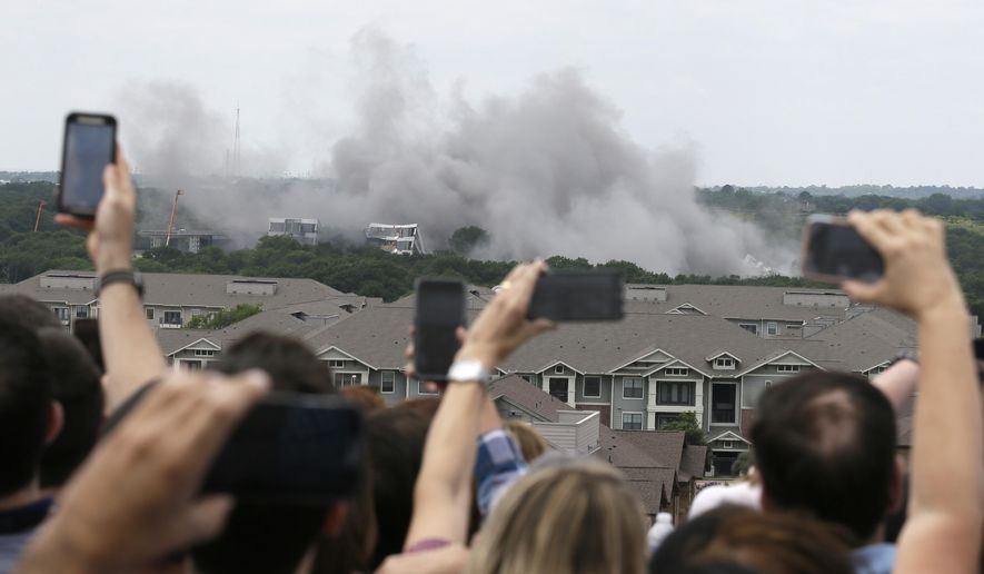 American Airlines employees look on and shoot video of the implosion of the company's former headquarters building in Fort Worth, Texas, Friday, May 20, 2016. (AP Photo/LM Otero)