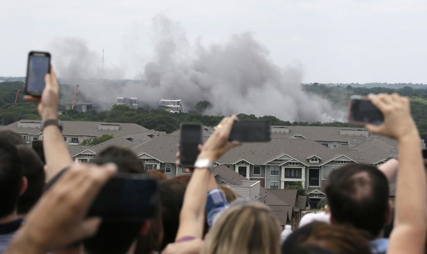 American Airlines employees look on and shoot video of the implosion of the company's former headquarters building in Fort Worth, Texas, Friday, May 20, 2016. (AP Photo/LM Otero)