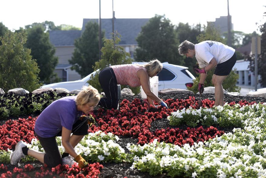 ADVANCE FOR WEEKEND EDITIONS - In this Tuesday, June 23, 2015 photo, three volunteers Elizabeth Bond, from left, Missy Pletcher and Nancy Laborde weed the Premier Arts Quilt Garden in Elkhart, Ind. They cleared weeds and replanted begonias to keep the garden looking good and healthy. (J. Tyler Klassen/The Elkhart Truth) MANDATORY CREDIT