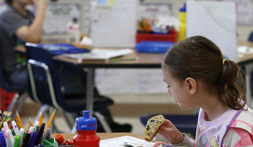 ADVANCE FOR WEEKEND EDITIONS MAY 21-22 - In this May 12, 2016 photo, Second-grader Ava Hart eats breakfast while working on a math worksheet in Libby Ettinger's classroom at Riverside Central Elementary School in Rochester, Minn. Riverside participates in the breakfast program which provides all students with free breakfast. School leadership says the program has reduced behavioral problems. (Andrew Link/The Rochester Post-Bulletin via AP) MANDATORY CREDIT