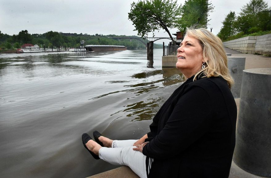 FOR RELEASE MONDAY, MAY 23, 2016, AT 12:01 A.M. CDT. - Jody Martinez lifts her feet so as not to get wet from the wake of a passing barge on the Mississippi River at Chestnut Plaza in the Upper Landing Park in St. Paul, Minn. on Wednesday, May 11, 2016. "This is a working river," she said. "People forget." Martinez, the lead designer of parks in a city known for them, is about to retire. (Jean Pieri/Pioneer Press via AP) MANDATORY CREDIT