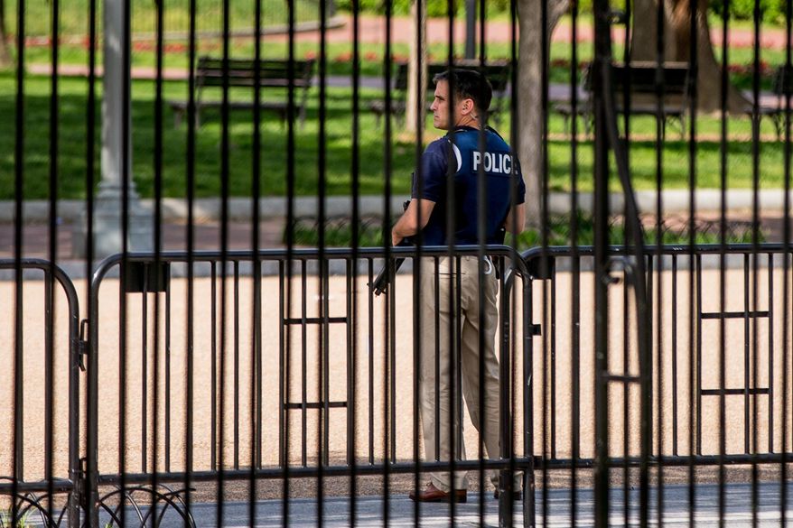 A security agent stands nearby the Northwest gate of the White House in Washington, Friday, May 20, 2016, after the White House is placed on lockdown for a shooting nearby. (AP Photo/Andrew Harnik)