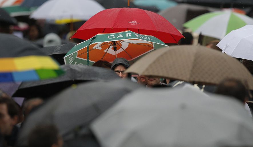 Spectators with umbrellas leave the courts as rain interrupted first round matches of the French Open tennis tournament at Roland Garros stadium in Paris, France, Sunday, May 22, 2016. (AP Photo/Christophe Ena)