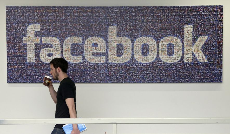 A Facebook employee walks past a sign at Facebook headquarters in Menlo Park, Calif. (Associated Press)