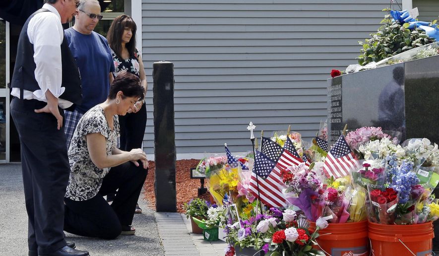 Mourners, including Jennifer Bohn, kneeling, her husband Randy Bohn, center, and Scott Veau, left, pause before a memorial set up for slain police Officer Ronald Tarentino outside the police station, Monday, May 23, 2016, in Auburn, Mass. Tarentino was fatally shot during a traffic stop in Auburn on Sunday morning, authorities said. (AP Photo/Elise Amendola)