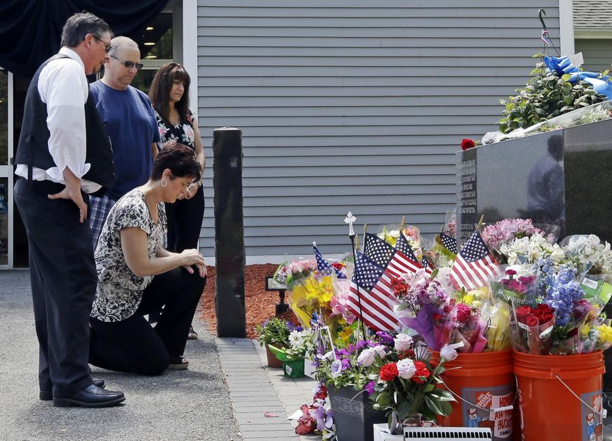 Mourners, including Jennifer Bohn, kneeling, her husband Randy Bohn, center, and Scott Veau, left, pause before a memorial set up for slain police Officer Ronald Tarentino outside the police station, Monday, May 23, 2016, in Auburn, Mass. Tarentino was fatally shot during a traffic stop in Auburn on Sunday morning, authorities said. (AP Photo/Elise Amendola)