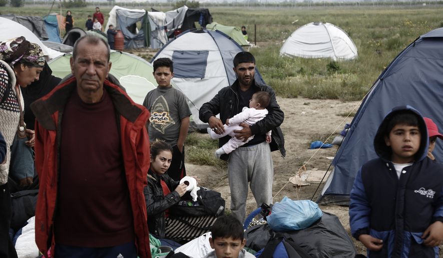 Refugees and migrants wait to embark into the buses during a police operation at a makeshift refugee camp at the Greek-Macedonian border near the northern Greek village of Idomeni, Tuesday, May 24, 2016. Greek authorities sent hundreds of police into the country's largest informal refugee camp at Tuesday to support the evacuation of the Idomeni site near the Macedonian border. (Yannis Kolesidis/ANA-MPA via AP)