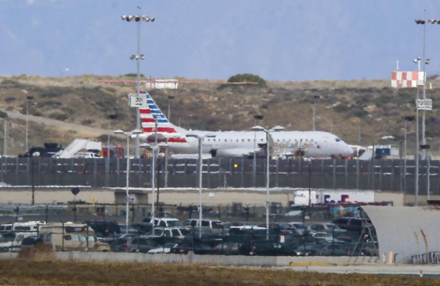 An American Airlines jet sits on a remote stretch of runway at Los Angeles International Airport Tuesday, May 24, 2016. American Airlines says officials screened the plane as a precaution after a "non-credible" threat was received about the flight from Houston. Passengers were escorted from the twin-engine regional jet more than an hour after it landed without incident Tuesday morning. A SWAT team with a dog went through the plane. (AP Photo/Damian Dovarganes)