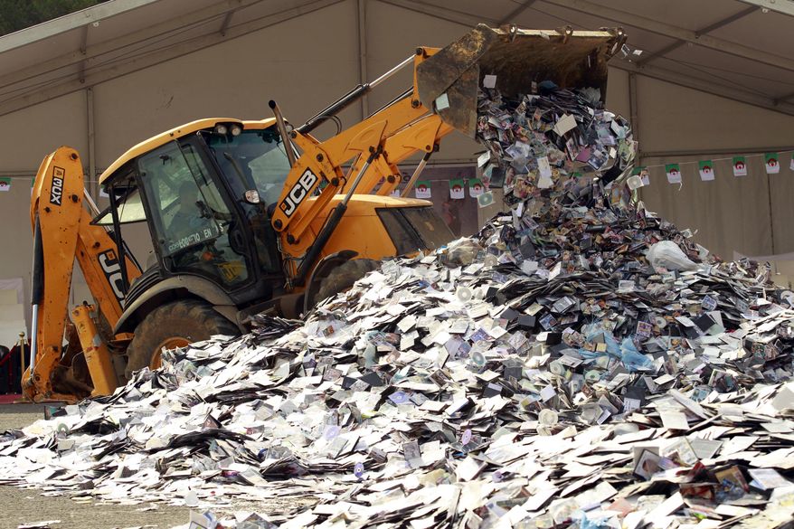 In this photo taken Monday, May 23, 2016, a backoe-loader crushes illegally made CDs and DVDs in the Algerian capital, Algiers. Power shovels and bulldozers have destroyed a huge mound of 2 million illegally copied CDs and DVDs outside Algeria’s Culture Ministry, as part of a government pledge to crack down on long-rampant piracy. (AP Photo)