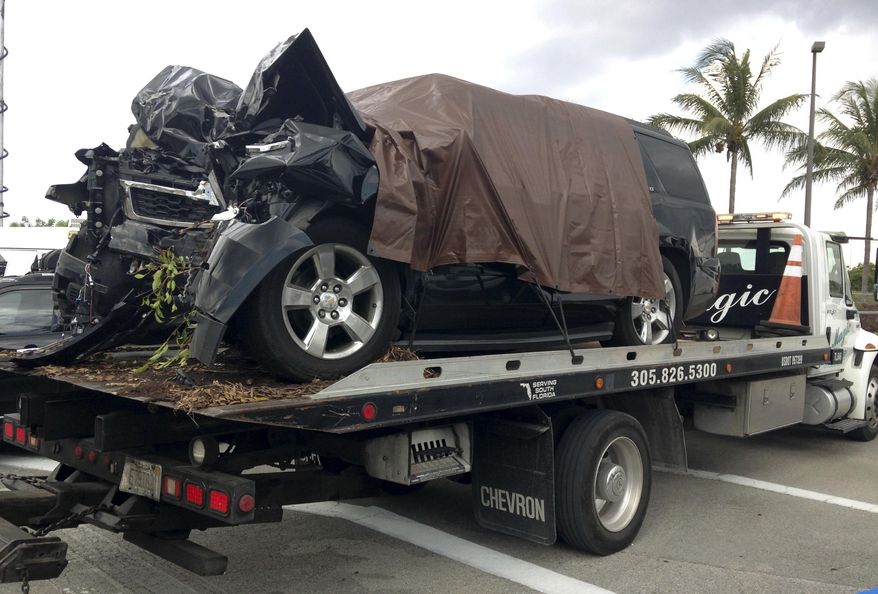 A tow truck leaves with City of Opa-locka Commissioner Terence Pinder's SUV after it crashed into a tree, Tuesday, May 24, 2016, at Miami-Opa Locka Executive Airport. Pinder was killed in a suspicious single-vehicle crash a day before he was scheduled to surrender in a criminal corruption case. Police said they are investigating whether the crash was deliberate. (AP Photo/Curt Anderson)