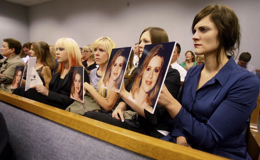 FILE - In this Aug. 27, 2012 file photo, family members hold up photos of Michele MacNeill facing Martin MacNeill as he enters the courtroom in Provo, Utah. MacNeill, who was found guilty of giving his wife drugs prescribed after cosmetic surgery and leaving her to drown in the bathtub of their home in 2007 so he could begin a new life with his mistress, will appear before a state appeals court Tuesday, May 24, 2016, in a long shot attempt to get his conviction overturned based on disputed testimony from a former cellmate. (Scott G Winterton/The Deseret News via AP, Pool, File)
