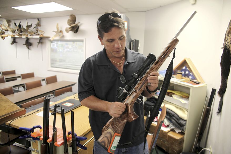 FILE - In this May 10, 2016, file photo, Jerry Ilo holds a gun that he uses to teach the Hawaii Department of Natural Resources hunter education training course in a classroom in Honolulu. Ilo was one of several Hawaii residents to speak out against a bill passed by lawmakers to allow Hawaii gun owners to be registered in a federal database that will automatically notify police if an island resident is arrested anywhere else in the country. (AP Photo/Marina Riker, File)