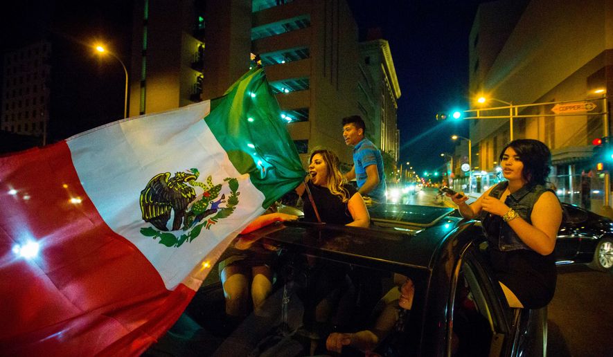 A woman waves the Mexican flag while driving past the Albuquerque Convention Center after a rally by Republican presidential candidate Donald Trump in Albuquerque, N.M., May 24, 2016. (Jett Loe/The Las Cruces Sun-News via AP)