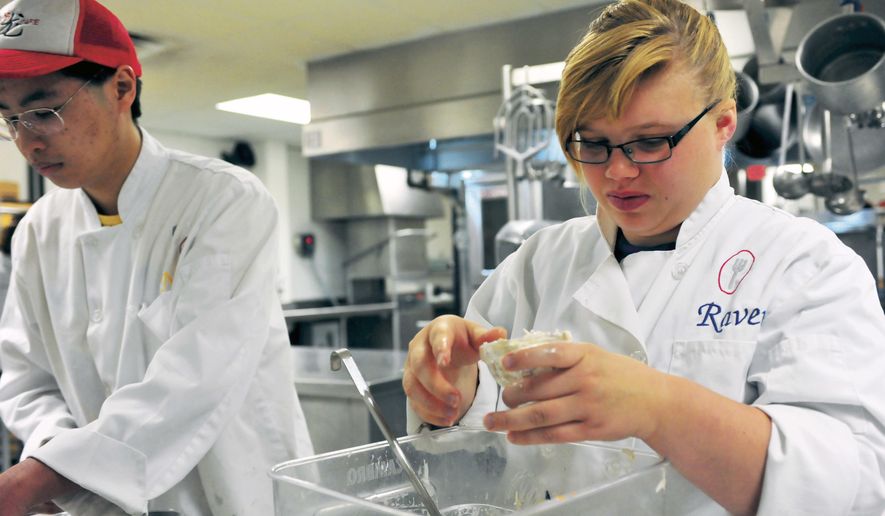In this May 3, 2016, photo, Pekin Community High School students Raven Bong and Neil Ly Payia prepare coleslaw at the school in Pekin, Ill. The two are enrolled in a program that teaches students real-life culinary and service skills. (Robert Downen/The Pekin Times via AP) MANDATORY CREDIT