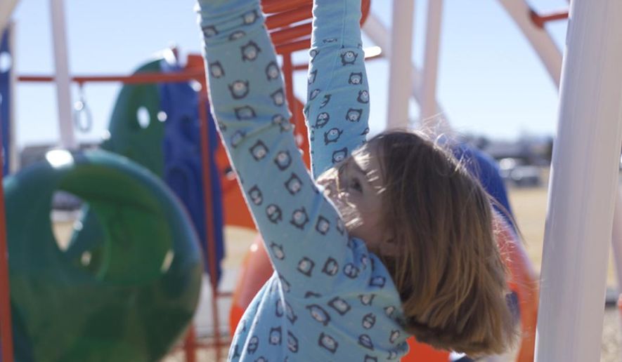 ADVANCE FOR THE WEEKEND OF MAY 28-29 AND THEREAFTER - Krysta Hubbard climbs the monkey bars on the playground at Westside Elementary School in Powell, Wyo. Though Krysta was born with sight, she lost most of her vision due to a brain tumor when she was 2 years old. Just as she’s not held back on the playground, Krysta’s family and teachers don’t want her to have any limitations in the classroom. (Carla Wensky/Powell Tribune via AP)