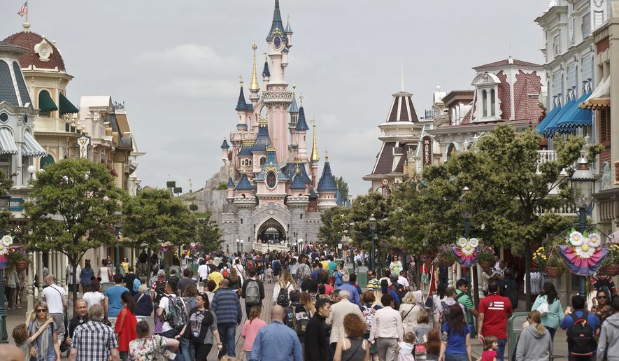 FILE - In this May 12, 2015, file photo, visitors walk near Sleeping Beauty's Castle at Disneyland Paris, in Marne la Vallee, east of Paris. The Euro Disney group is going on trial in France, Wednesday May 25, 2016, for publishing an allegedly discriminatory job ad requesting that candidates have "European citizenship" to work as parade artists at its famous Disneyland Paris theme park. (AP Photo/Michel Euler, File)