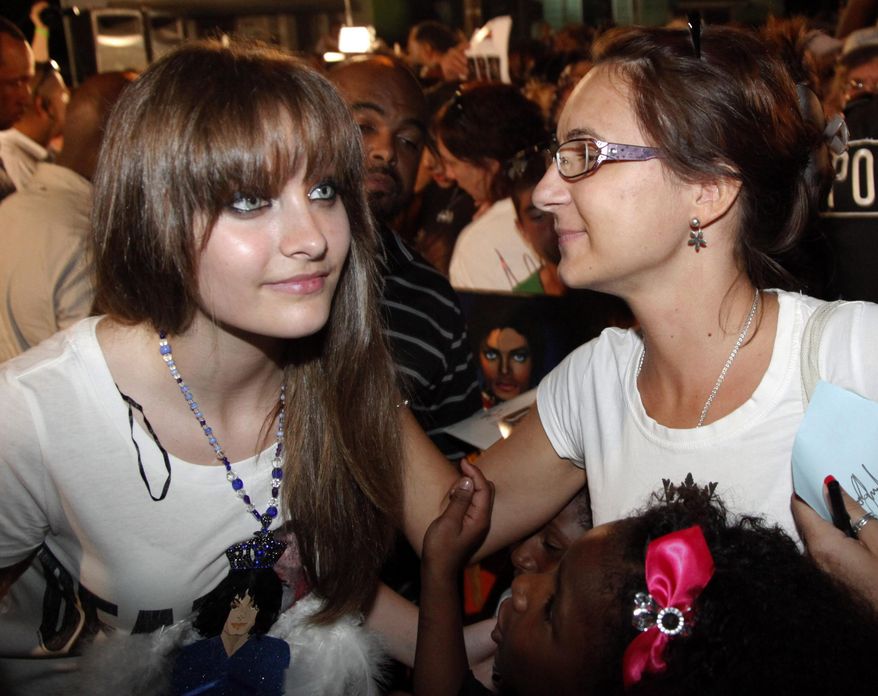 This Aug. 29, 2012, file photo shows Paris Jackson, left, daughter of the late pop icon Michael Jackson, poses with a fan outside Jackson's boyhood home during a celebration on what would have been Jackson's 54th birthday in Gary, Ind. Jackson revealed a new tattoo on May 23, 2016, that honors her father. (AP Photo/Charles Rex Arbogast, File)