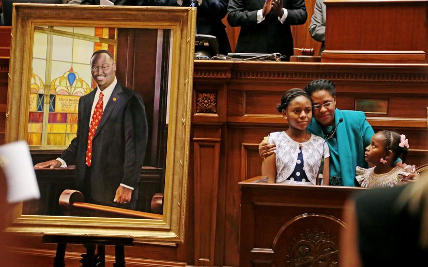 Jennifer Pinckney and daughters Eliana and Malana embrace after unveiling of the portrait of slain state Sen. Clementa Pinckney at the state Capitol, Wednesday, May 25, 2016, in Columbia, S.C. Clementa Pinckney died in that church along with eight others on June 17, leading a nighttime Bible study. Police said they were gunned down by a man motivated by racial hatred. (Gerry Melendez/The State via AP)