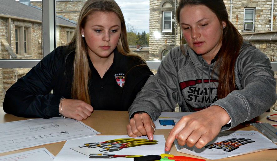 Shattuck St. Mary’s juniors Maddie Mills, left, and Brette Pettet are working on an engineering project to create a prosthetic hand for Bethlehem Academy eighth-grader Elizabeth Stroh. Stroh was born without the majority of her left hand and fingers. (Philip Weyhe/Faribault Daily News via AP)