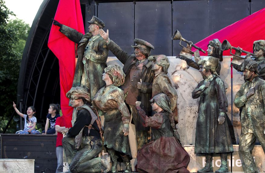 In this May 22, 2016, picture actors perform in Lenin's Arc play, staged by the Masca Theatre in Bucharest, Romania. Romanians relive the horrors of communism in a play featuring Lenin and Stalin, set to patriotic songs of that era, played by actors who mime their roles, the hour-long performance in a Bucharest park, also being a reminder for some that not everything was bad under communism.(AP Photo/Vadim Ghirda)