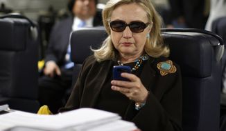 Then-Secretary of State Hillary Rodham Clinton checks her Blackberry from a desk inside a C-17 military plane upon her departure from Malta, in the Mediterranean Sea, bound for Tripoli, Libya, on Oct. 18, 2011. (AP Photo/Kevin Lamarque, Pool, File) ** FILE **