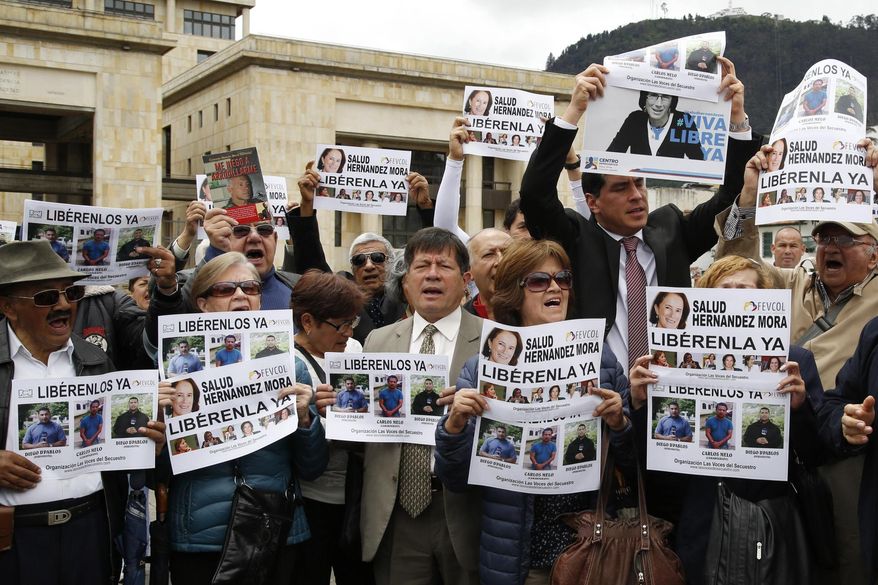 Demonstrators hold signs to demand the release of three journalists who are believe to have been taken hostage, during a sit-in in Bogota, Colombia, Wednesday, May 25, 2016. Salud Hernandez-Mora, correspondent in Colombia for Spain's El Mundo and columnist for the Bogota daily El Tiempo, as well as Diego D'Pablos and Carlos Melo, journalists at the local TV network RCN, are reported missing on the northeastern Colombia's border with Venezuela, a mountainous area dominated by leftist rebels and drug-traffickers. (AP Photo/Fernando Vergara)