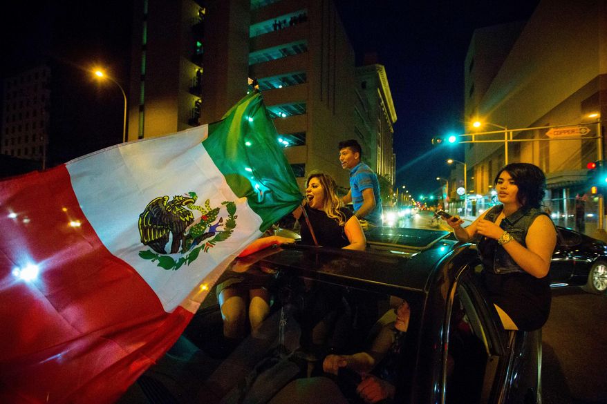In this May 24, 2016, photo, a woman waves the Mexican flag while driving past the Albuquerque Convention Center after a rally by Republican presidential candidate Donald Trump in Albuquerque, N.M. Hispanic voters in Florida, New Mexico and California have waved Mexican flags and bashed Donald Trump piñatas to protest the Republican presidential contender’s hard line approach to immigration.Yet far from the protests, an increasingly vocal Hispanic minority is speaking out in favor of the brash billionaire. (Jett Loe/The Las Cruces Sun-News via AP) MANDATORY