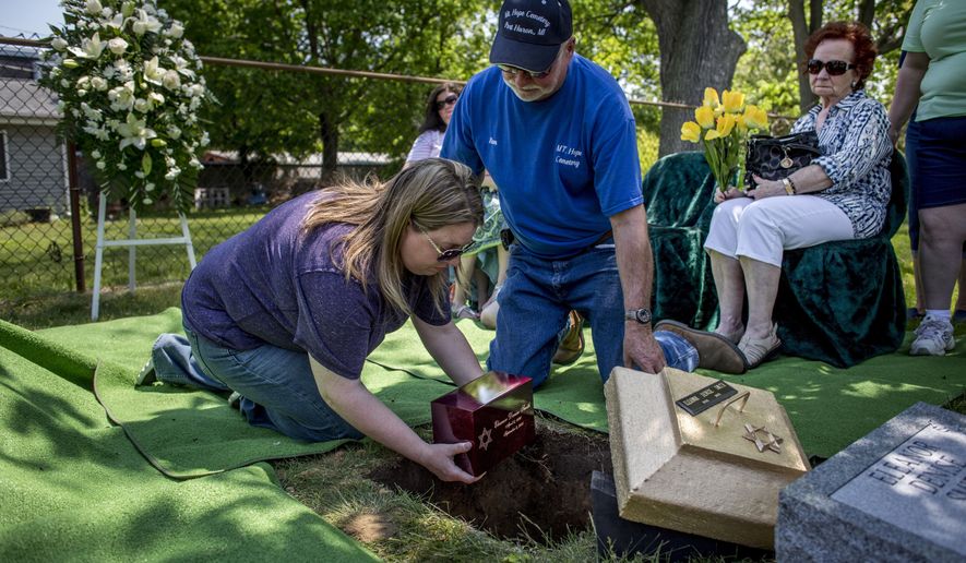 Audrie Friedland places an urn containing the ashes of Eleanor Denise Smith in the ground as Ron Ceglarek and Bobby Jean King, right, look on Wednesday, May 26, 2016 at Mount Sinai Cemetery in Port Huron, Mich. Smith was fatally injured in a hit-and-run on Sept. 2, 2015. The service was funded through donations that was established by Michael Kolb, of Harold W. Vick Funeral Home in Mount Clemens after no family came forward to claim her. (Jeffrey M. Smith/The Times Herald via AP) NO SALES; MANDATORY CREDIT