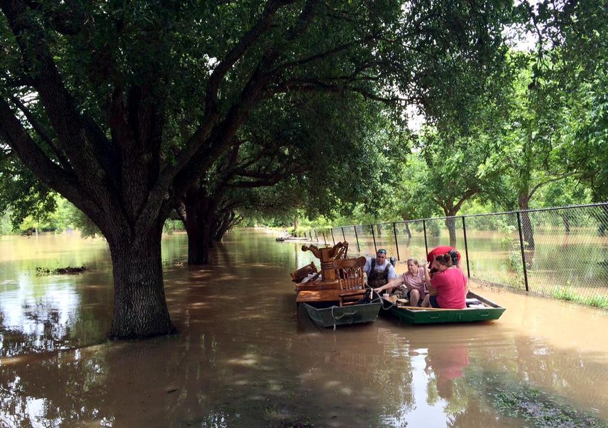 Dustin Toll, left, and other family members use two boats on Wednesday, June 1, 2016, to remove furniture from the mobile home of his grandparents, which had been flooded by the Brazos River in Rosenberg, Texas. (AP Photo/Juan Lozano)
