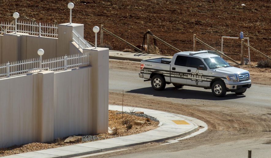 FILE - In this Feb. 18, 2013, file photo, a Marshal with the FLDS Hildale/Colorado City Town Marshals patrols along the walls of a compound built for imprisoned leader Warren Jeffs in Hildale, Utah. Two polygamous towns on the Arizona-Utah line are vigorously opposing a bid to disband their shared police department as a way to remedy religious-based discrimination against nonbelievers, saying problems at the agency don't require such a drastic step. (Trent Nelson/Salt Lake Tribune via AP, File) MANDATORY CREDIT