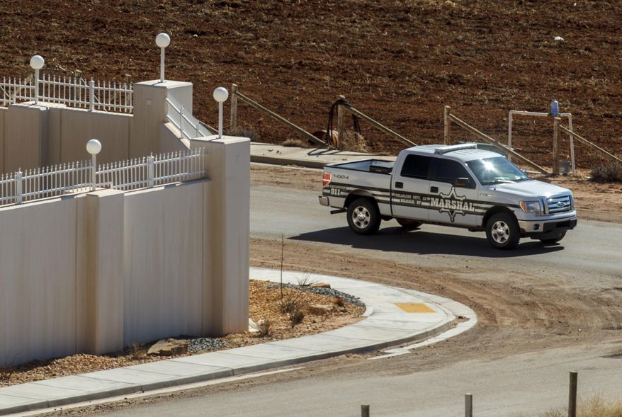 FILE - In this Feb. 18, 2013, file photo, a Marshal with the FLDS Hildale/Colorado City Town Marshals patrols along the walls of a compound built for imprisoned leader Warren Jeffs in Hildale, Utah. Two polygamous towns on the Arizona-Utah line are vigorously opposing a bid to disband their shared police department as a way to remedy religious-based discrimination against nonbelievers, saying problems at the agency don't require such a drastic step. (Trent Nelson/Salt Lake Tribune via AP, File) MANDATORY CREDIT