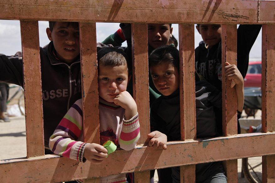 In this April 14, 2016 photo, Syrian refugees look through the gate of a grocery store at the al-Azraq refugee camp in northeast Jordan. Thousands of newly arrived Syrian refugees have been moved behind barbed wire in a separate section of the Azraq camp because Jordan considers them potential security risks. Aid groups agreed to isolate the newcomers to allay Jordanian security concerns and help speed up admissions of 64,000 refugees stranded in remote desert areas on the kingdom’s border. But the new arrangement is barely making a dent, and crowds on the border are expected to grow to 100,000 by the end of the year. (AP Photo/Sam McNeil)