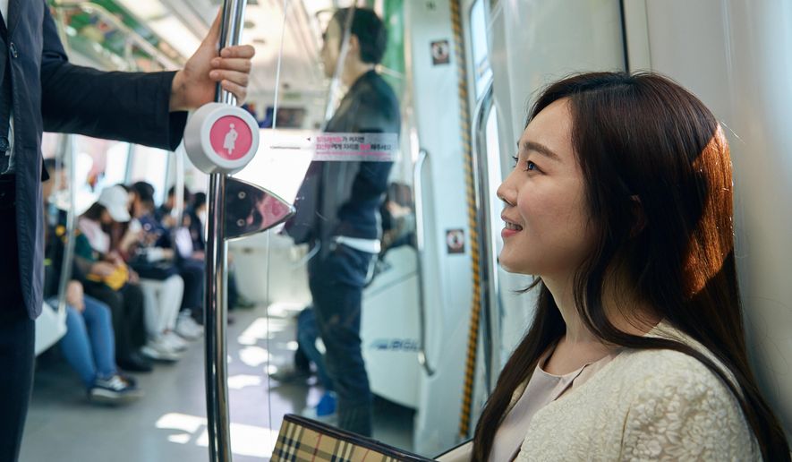 In this Wednesday, April 6, 2016 photo provided by Busan Metropolitan City, a woman sits on special priority seats next to a metal bar attached with a "pink light" wireless sensor in a subway train in Busan, South Korea. South Korea's second-largest city of Busan is testing a wireless technology it hopes can alleviate such problems and perhaps help address one of the biggest challenges facing the Asian country: a stubbornly low birthrate. (Kwon Sung-hoon/Busan Metropolitan City via AP)