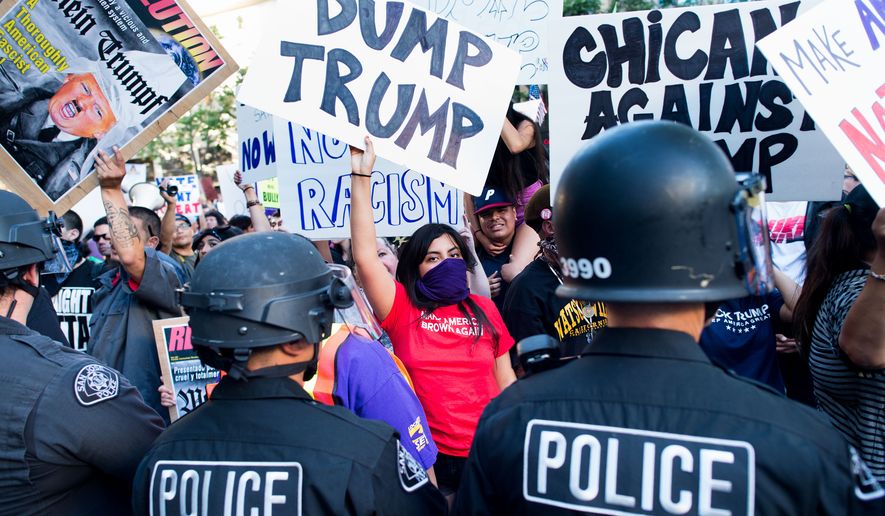 Police form a line to contain protesters outside a campaign rally for Republican presidential candidate Donald Trump on Thursday, June 2, 2016, in San Jose, Calif.  A group of protesters attacked  Trump supporters who were leaving the presidential candidate&#x27;s rally in San Jose on Thursday night. A dozen or more people were punched, at least one person was pelted with an egg and Trump hats grabbed from supporters were set on fire on the ground. (AP Photo/Noah Berger)