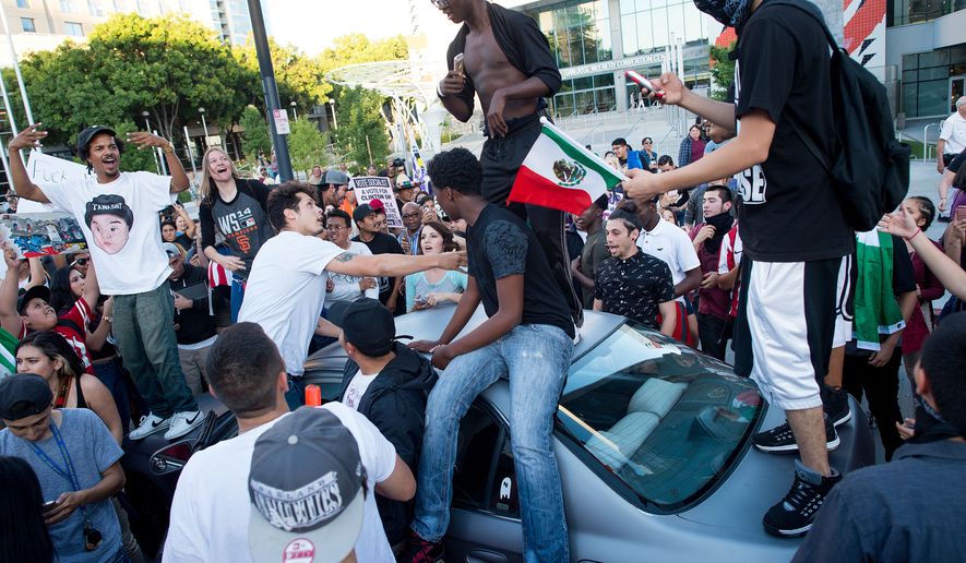 Protesters against Republican presidential candidate Donald Trump climb on a car outside a Trump campaign rally on Thursday, June 2, 2016, in San Jose, Calif. A group of protesters attacked Trump supporters who were leaving the candidate&#x27;s rally in San Jose on Thursday night. A dozen or more people were punched, at least one person was pelted with an egg and Trump hats grabbed from supporters were set on fire on the ground. (AP Photo/Noah Berger)
