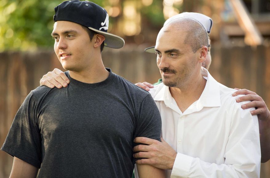 In this Friday, June 3, 2016 photo, Weldon Angelos, right, holds his son Anthoney in Sandy, Utah. Weldon Angelos, a Utah music producer who was ordered to 55 years behind bars for bringing guns to marijuana deals has been set free, after 12 years in prison and national outcry over the mandatory minimum sentencing laws that forced a federal judge to impose the lengthy term. (Rick Egan/The Salt Lake Tribune via AP) DESERET NEWS OUT; LOCAL TELEVISION OUT; MAGS OUT; MANDATORY CREDIT